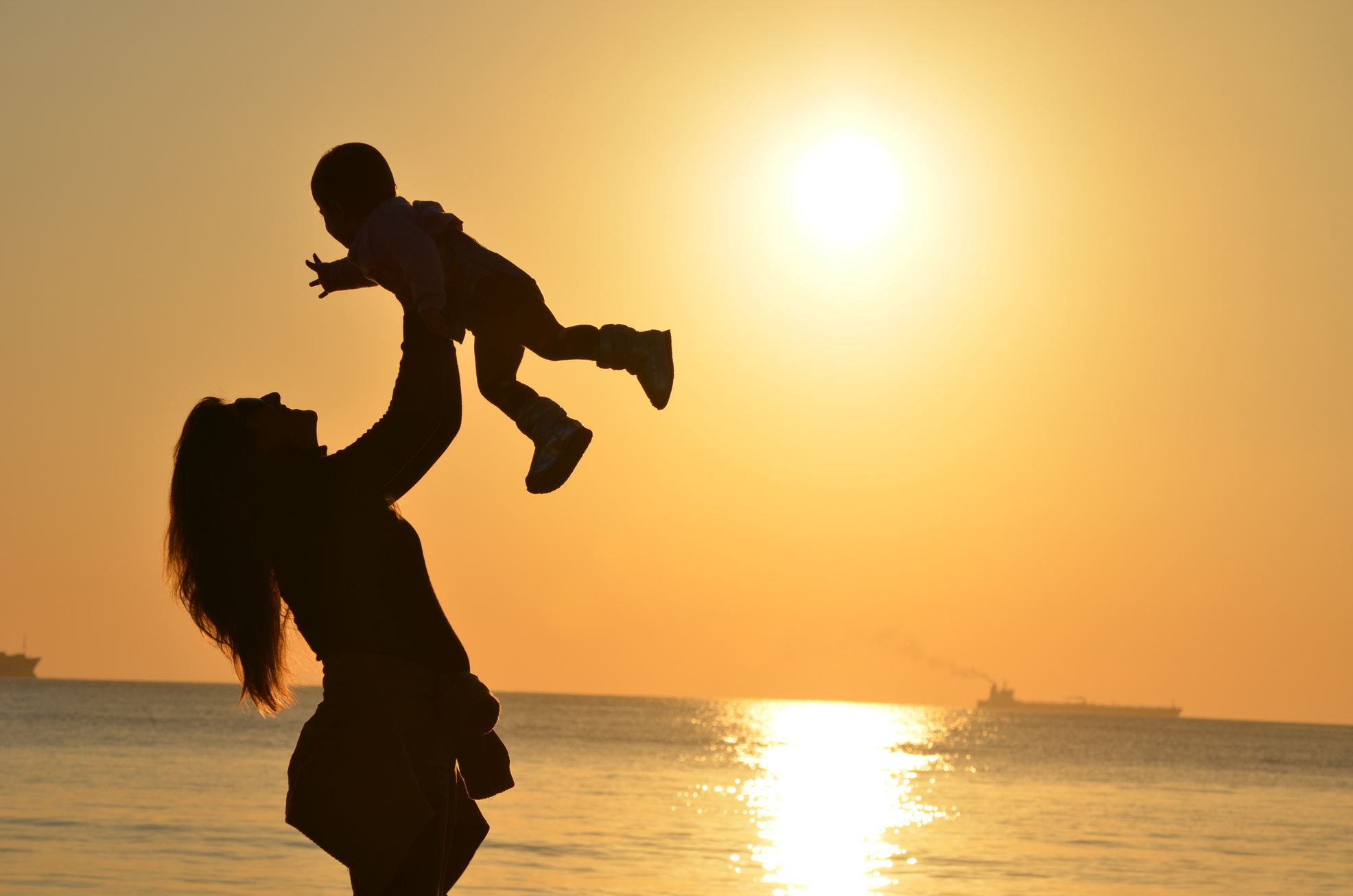 Silhouette of a Mother Carrying Child on the Beach